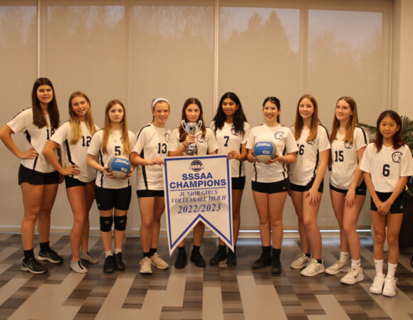 WCRA female students holding up volleyball championship trophy and banner